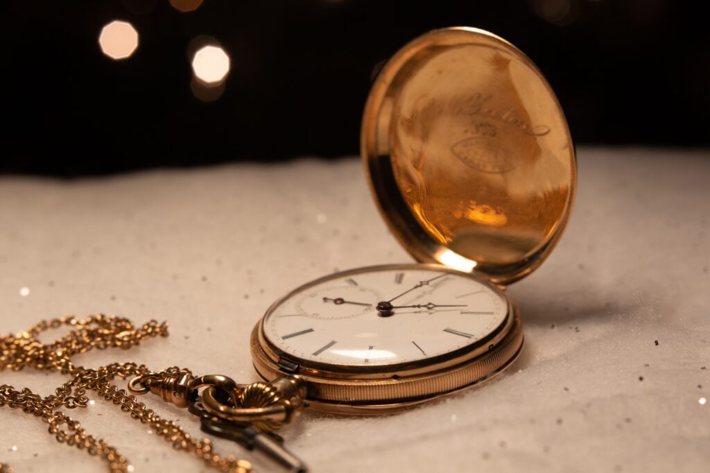Antique gold pocket watch with chain and key. White clock face.